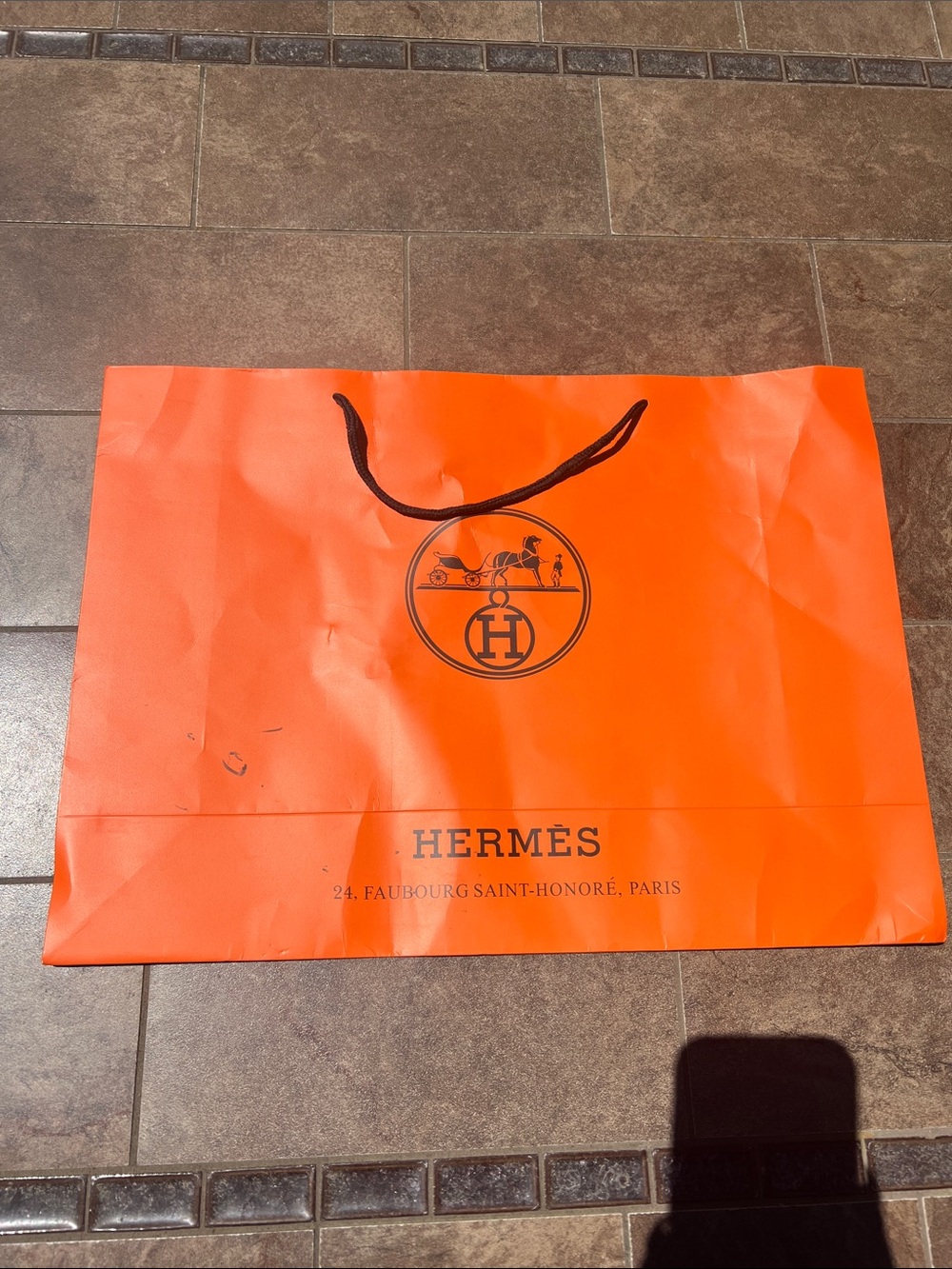 Hermès Orange Branded Shopping Bag with rope handles.